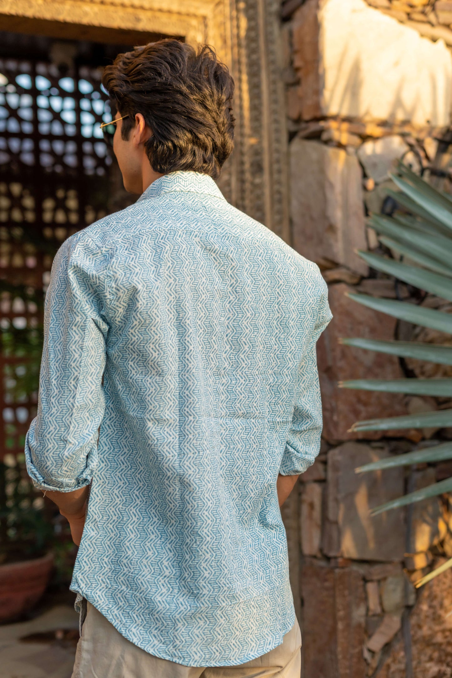 back view of a man featuring a white kantha work shirt with blue tribal print