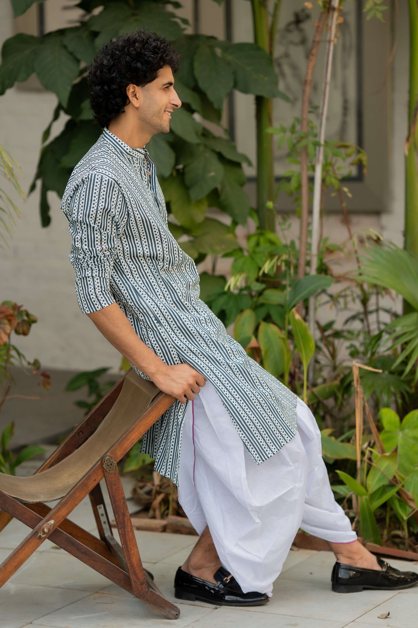 Indian man wearing a white long kurta featuring blue stripe print.