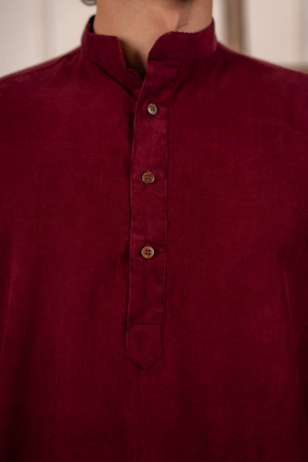 Maroon shirt with button details on a neutral background