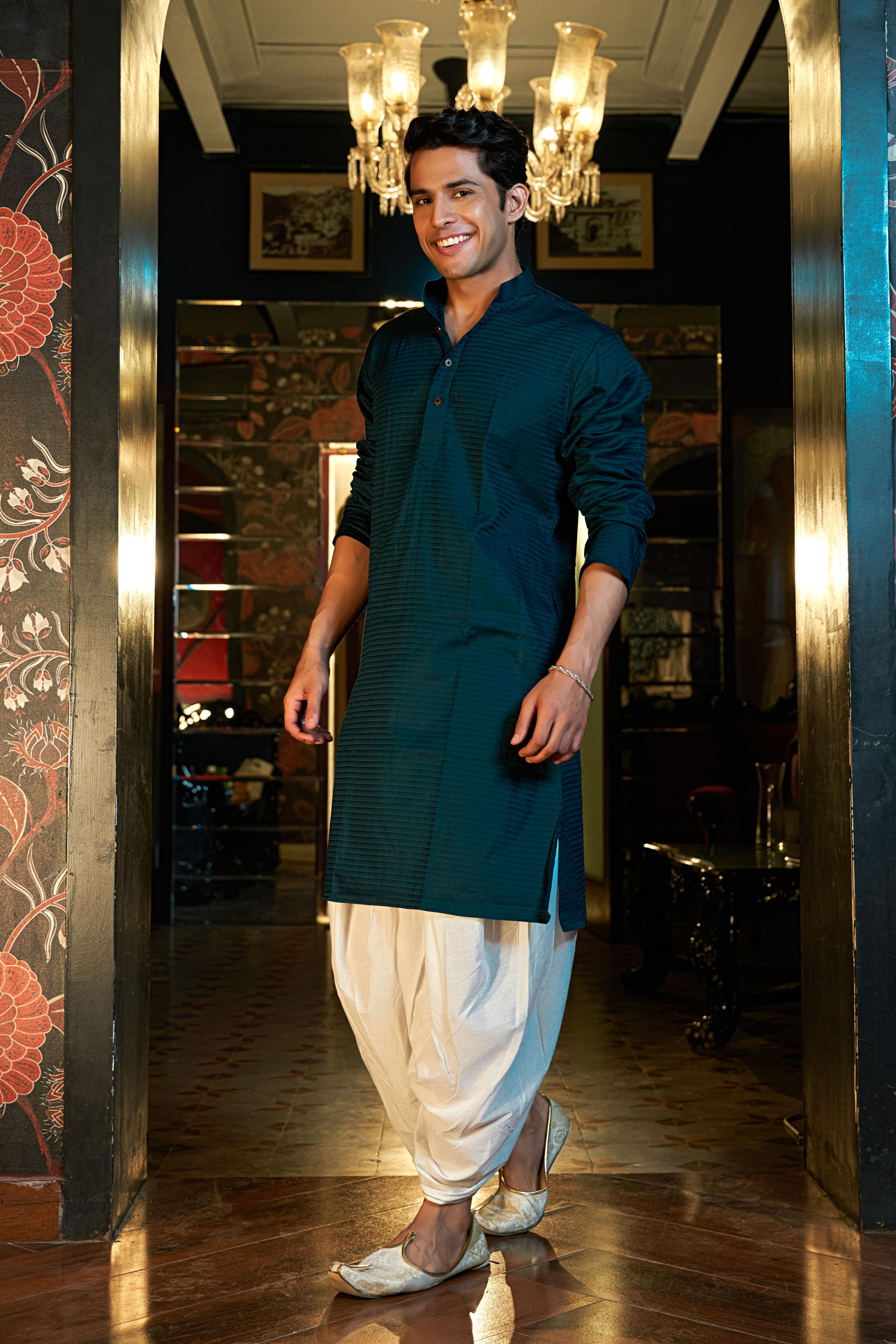 men's blue kurta worn by an indian man. Pairing it with a dhoti and traditional indian shoes called jutties. 