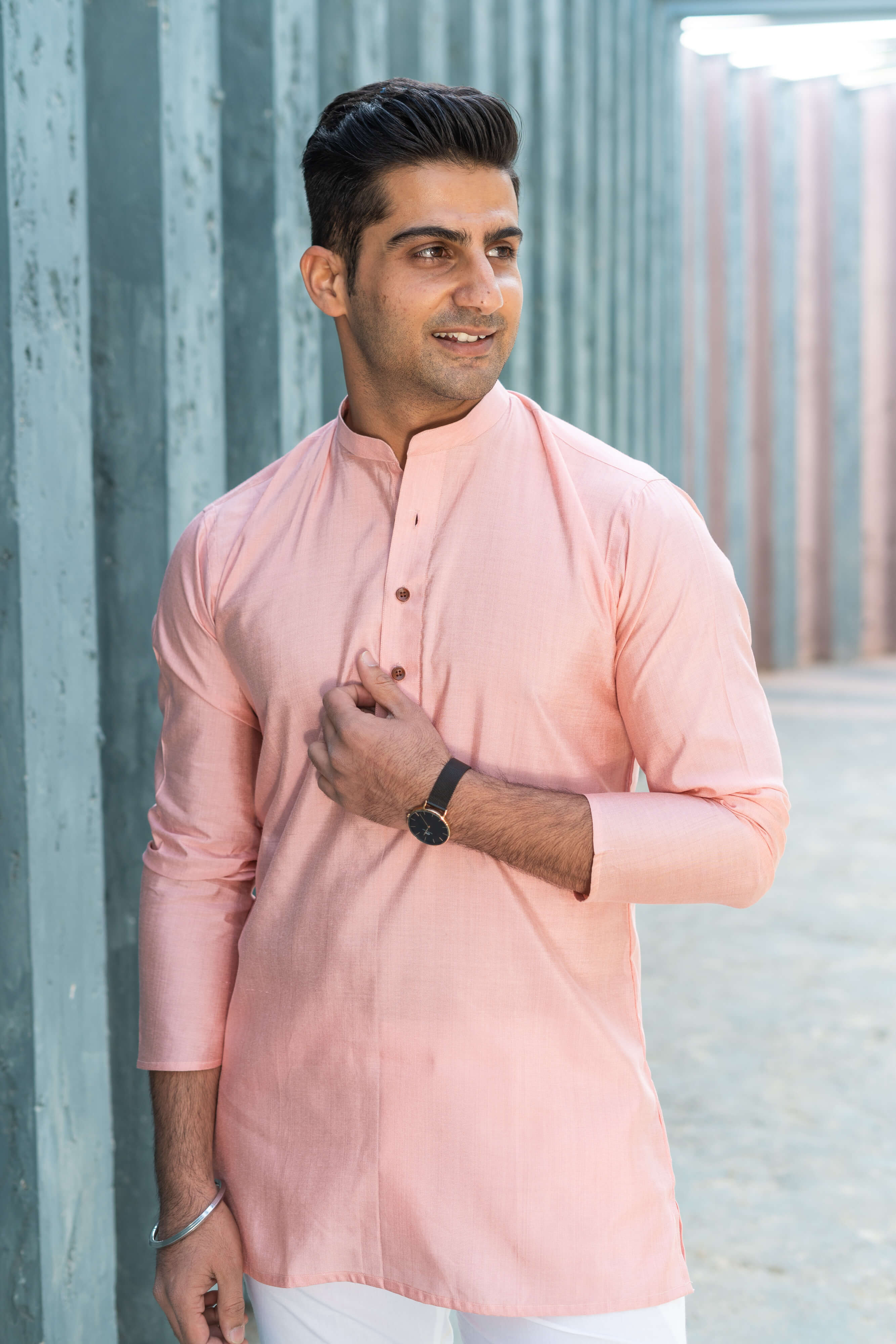 An Indian men wearing a pink color short kurta with a black wristwatch