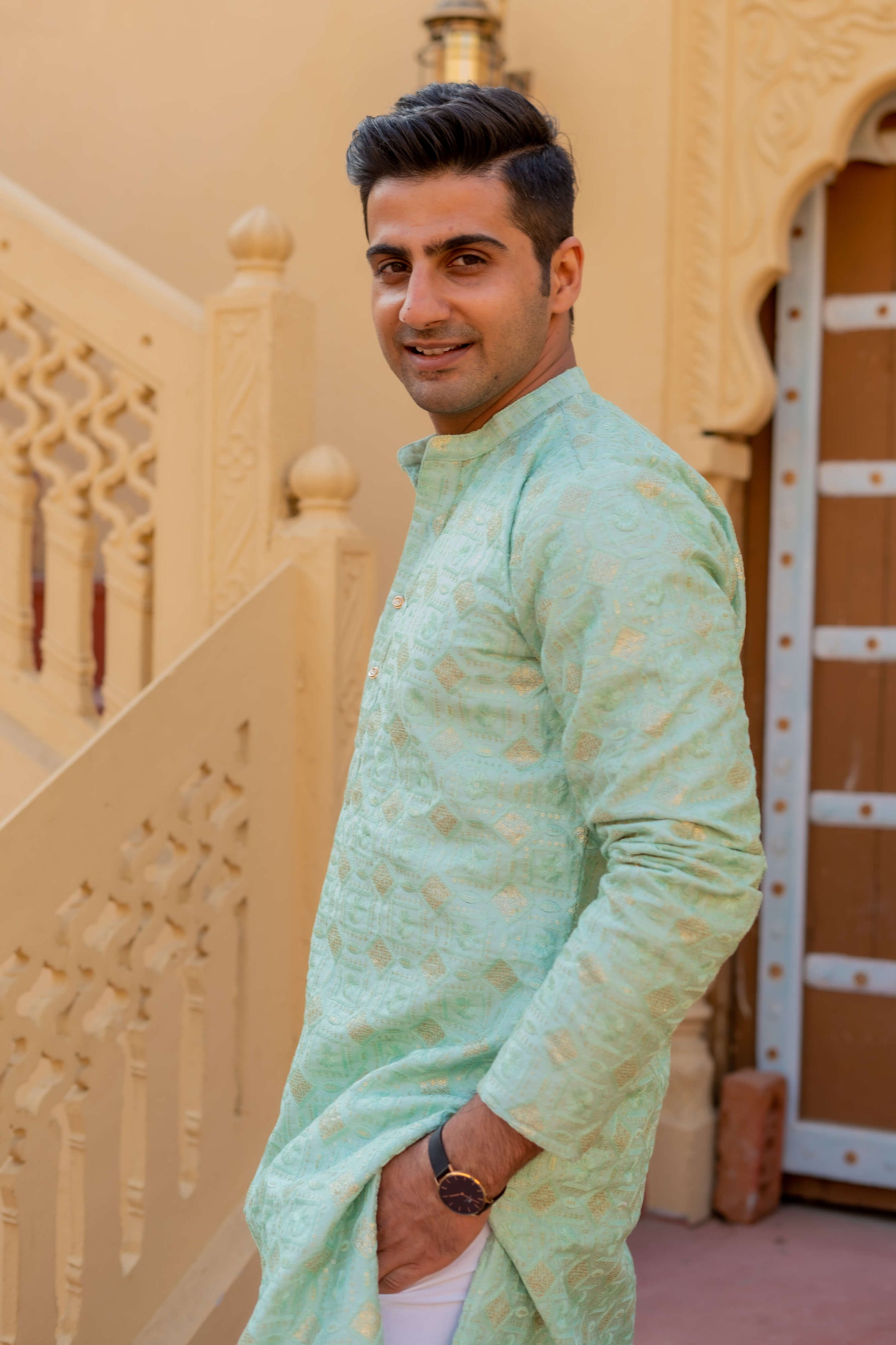 Indian man wearing a sea green long kurta with embroidery work. 