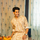 An Indian man wearing a brown color long kurta with an off-white floral print sitting on a table