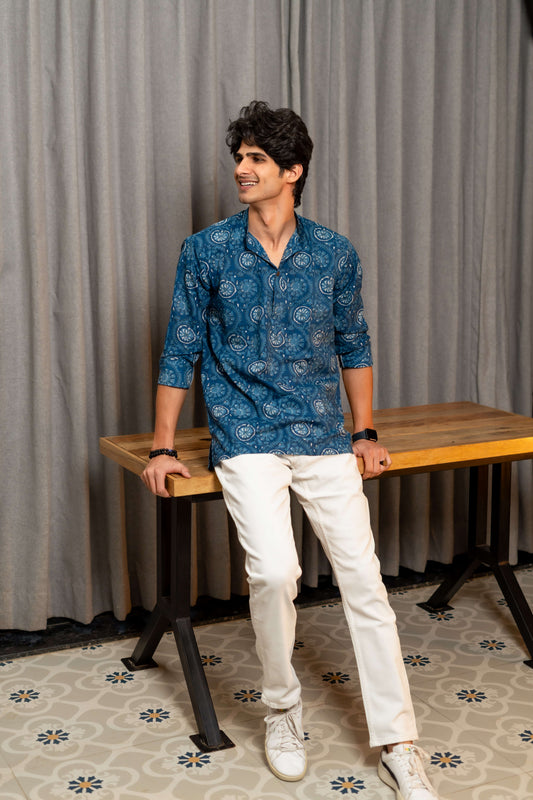 Indian men wearing a blue color short kurta with white floral print. styled  with a white jeans and white sneaker. 