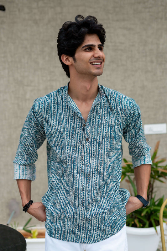 a white printed short kurta for men worn by an Indian men. smiling at camera. 