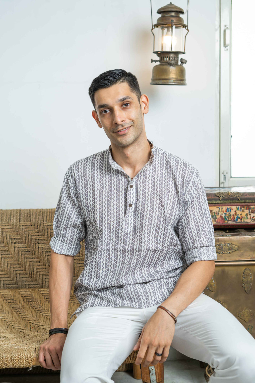 Indian man wearing a white tribal print short kurta for men.
